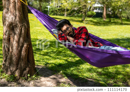 Man in a hammock feeling relaxed and rested Man in a hammock feeling relaxed and rested 111114170