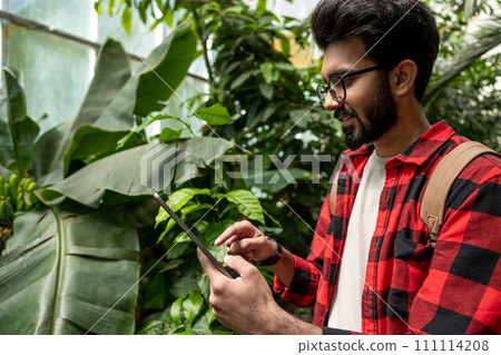 Hindu man with tablet in hands in botanical garden Hindu man with tablet in hands in botanical garden 111114208