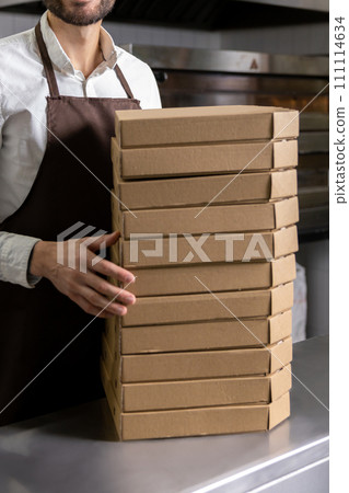 Male service man with many pizza boxes in pizzeria 111114634
