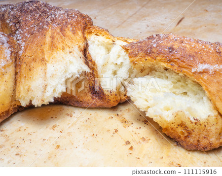 Wicker bun with cinnamon and sugar. Broken wicker bun. Bread product of an unusual shape. Homemade baking. Close-up of food. Pulp baking. Wicker bun with cinnamon and sugar. Broken wicker bun. Bread product of an unusual shape. Homemade baking. Close-up of food. Pulp baking. 111115916