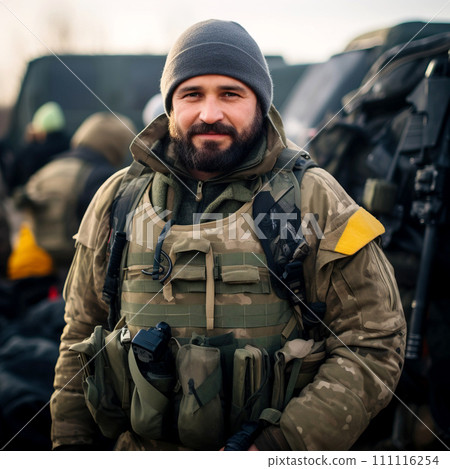A military man in winter camouflage clothing on a blurred background of equipment and people. 111116254