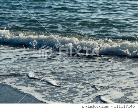 A photo looking down from a hill, with the waves crashing on the big ocean, the blue sky, the sun, and the setting sun mixing together. A photo looking down from a hill, with the waves crashing on the big ocean, the blue sky, the sun, and the setting sun mixing together. 111117140