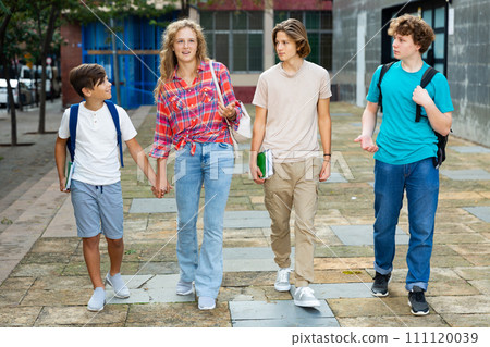 Four teenagers talking about play on walk in street Four teenagers talking about play on walk in street 111120039