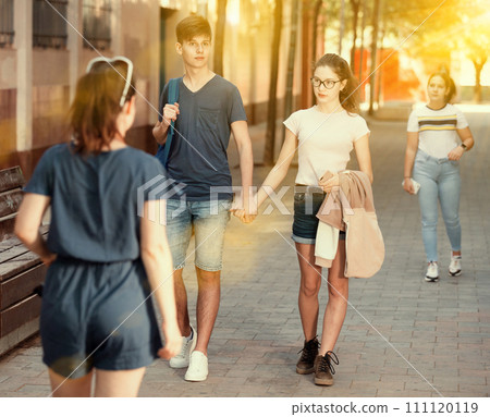 Happy teenage couple strolling along city street in summer 111120119
