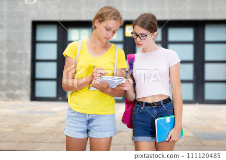Girls talking about homework outdoors 111120485