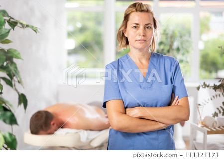 Female physiotherapist poses against background of spa salons office. Female physiotherapist poses against background of spa salons office. 111121171