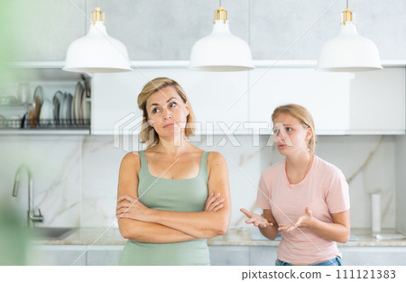 Agitated daughter imploringly asks angry mother for forgiveness. 111121383