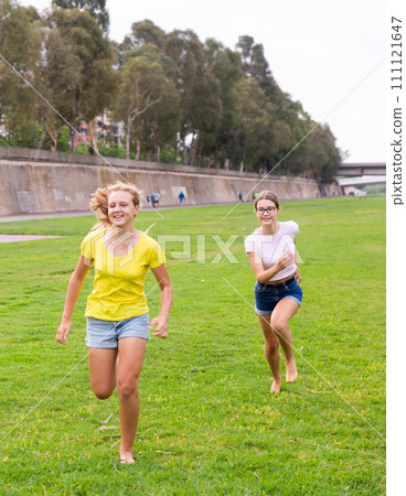 Laughing girlfriends are jogging together in park and having fun 111121647