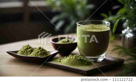 A steaming cup of warm green tea and a sprinkle of matcha powder in a small porcelain cup sit elegantly on the wooden table. 111122722