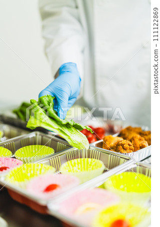 Young woman packing side dishes at a food factory, faceless Young woman packing side dishes at a food factory, faceless 111122869