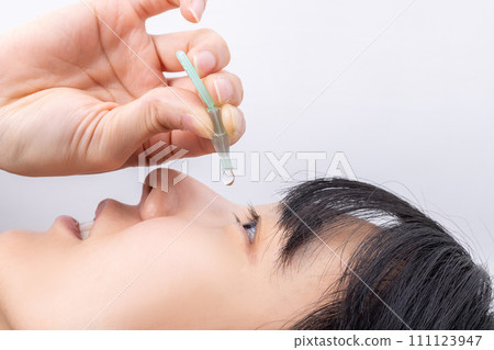 Woman applying eye drops 111123947
