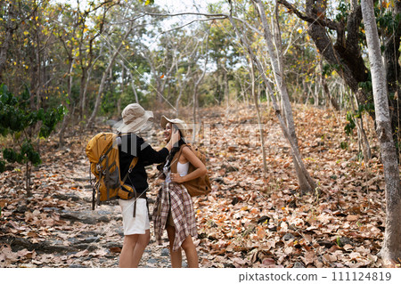 Happy LGBT Lesbian couple Travelers Hiking with Backpacks in forest Trail. LGBT Lesbian Couple Hikers with backpacks walks in mountains in vacation Happy LGBT Lesbian couple Travelers Hiking with Backpacks in forest Trail. LGBT Lesbian Couple Hikers with backpacks walks in mountains in vacation 111124819