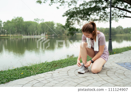 Active morning. Close up photo of woman in sport clothes tying shoelaces before running Active morning. Close up photo of woman in sport clothes tying shoelaces before running 111124907