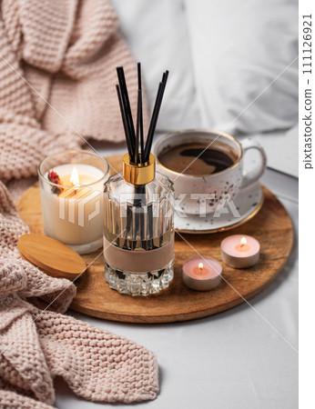 Bamboo sticks in bottle with scented candles and cup of coffee Bamboo sticks in bottle with scented candles and cup of coffee 111126921