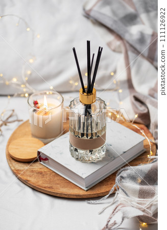 Home fragrance in glass bottle and bamboo sticks with scented candle, paper book. Home fragrance in glass bottle and bamboo sticks with scented candle, paper book. 111126922