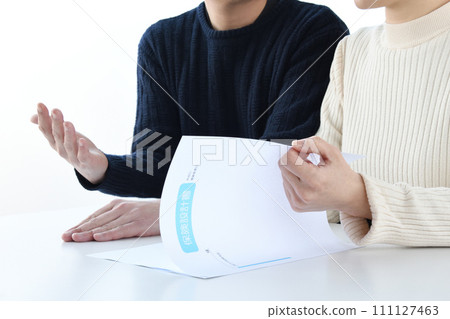 A couple looking at insurance materials and talking A couple looking at insurance materials and talking 111127463