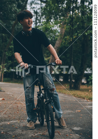 Young handsome bearded man taking a break while travelling the city with his bicycle using his digital tablet looking away thoughtfully 111128099
