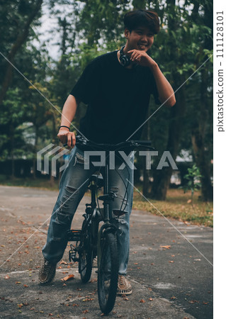 Young handsome bearded man taking a break while travelling the city with his bicycle using his digital tablet looking away thoughtfully 111128101