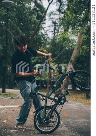 Young handsome bearded man taking a break while travelling the city with his bicycle using his digital tablet looking away thoughtfully 111128121