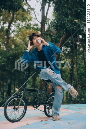 Young handsome bearded man taking a break while travelling the city with his bicycle using his digital tablet looking away thoughtfully 111128140