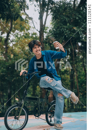 Young handsome bearded man taking a break while travelling the city with his bicycle using his digital tablet looking away thoughtfully Young handsome bearded man taking a break while travelling the city with his bicycle using his digital tablet looking away thoughtfully 111128141