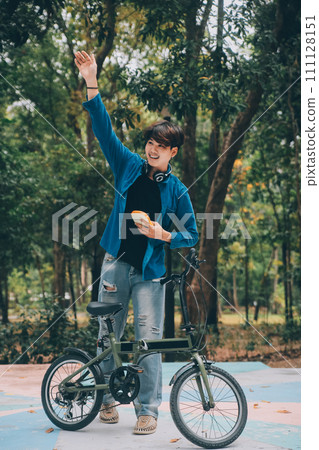 Young handsome bearded man taking a break while travelling the city with his bicycle using his digital tablet looking away thoughtfully 111128151
