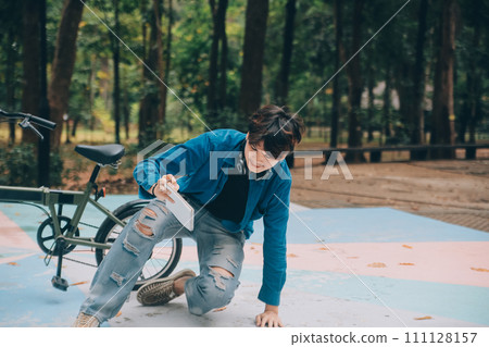 Young handsome bearded man taking a break while travelling the city with his bicycle using his digital tablet looking away thoughtfully Young handsome bearded man taking a break while travelling the city with his bicycle using his digital tablet looking away thoughtfully 111128157