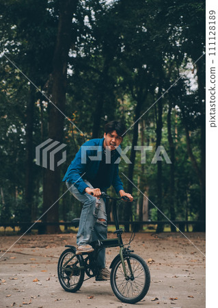 Young handsome bearded man taking a break while travelling the city with his bicycle using his digital tablet looking away thoughtfully Young handsome bearded man taking a break while travelling the city with his bicycle using his digital tablet looking away thoughtfully 111128189