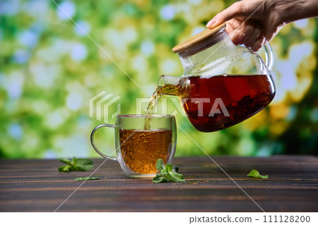 natural organic herbal tea pours in a glass from glass teapot 111128200