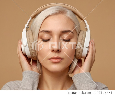 Close-up portrait of a young blonde woman wearing beige headphones. 111128861