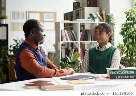 Portrait of Black senior professor talking to student in one on one meeting in class 111129102