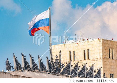 Waving national flag of russian federation on top of government stalin era empire building in Moscow Russia against bright blue sky Waving national flag of russian federation on top of government stalin era empire building in Moscow Russia against bright blue sky 111130229
