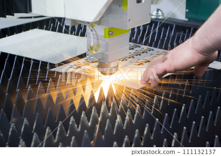Metal laser cutting. Cutting sheet of metal by laser metal cutting close-up. Industrial equipment machine for cutting metal in factory. Moving head with sparks. Metalwork manufacturing background Metal laser cutting. Cutting sheet of metal by laser metal cutting close-up. Industrial equipment machine for cutting metal in factory. Moving head with sparks. Metalwork manufacturing background 111132137