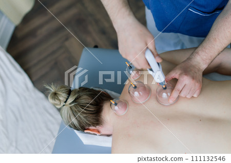 A woman does a hip massage with a vacuum jar for an anti-cellulite massage. A woman does a hip massage with a vacuum jar for an anti-cellulite massage. 111132546