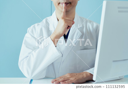 Male doctor putting his finger on his mouth Male doctor putting his finger on his mouth 111132595
