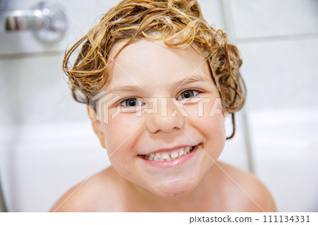 Cute child with shampoo foam and bubbles on hair taking bath. Portrait of happy smiling preschool girl health care and hygiene concept. Washes hair by herself. 111134331