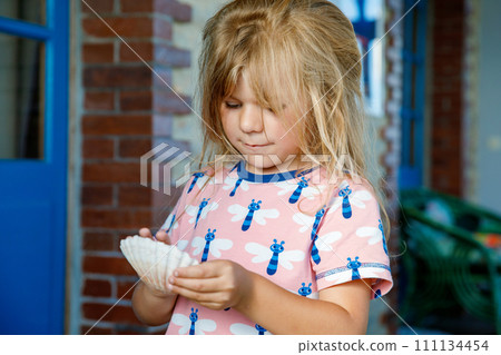 Little preschool girl with variation of different shells and clams at home. Happy child with collected shell from Normandy, France. Children, education, vacation concept. 111134454