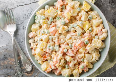 Delicious potato salad with green peas, carrots, corn and apple covered with mayonnaise close-up on a plate. Horizontal top view 111134735