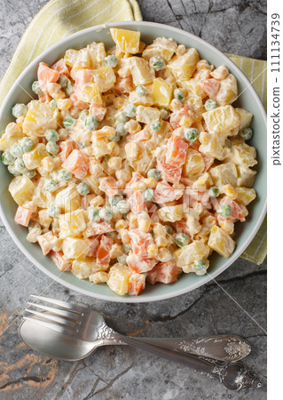 Brazilian gaucho salad is made with a combination of potatoes, carrots, peas, corn, green apples and mayonnaise closeup on the plate. Vertical top view Brazilian gaucho salad is made with a combination of potatoes, carrots, peas, corn, green apples and mayonnaise closeup on the plate. Vertical top view 111134739