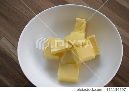 Butter slices are placed on a plate, Cut butter into cubes for baking cake Butter slices are placed on a plate, Cut butter into cubes for baking cake 111134897