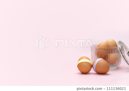 Decorated Easter eggs in ribbed glass on pink background. Simple holiday background Decorated Easter eggs in ribbed glass on pink background. Simple holiday background 111136021