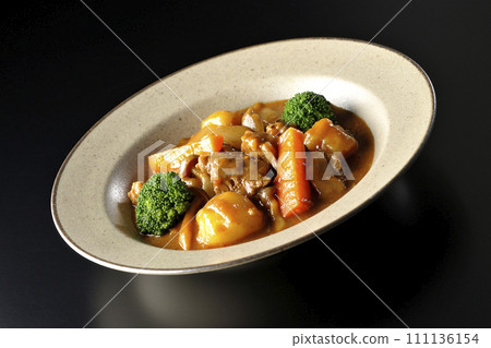 Beef stew with many ingredients such as broccoli, carrots, and shimeji mushrooms is photographed against a black background. 111136154