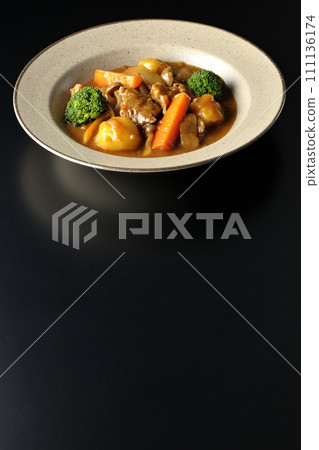 Beef stew with many ingredients such as broccoli, carrots, and shimeji mushrooms is photographed against a black background. Beef stew with many ingredients such as broccoli, carrots, and shimeji mushrooms is photographed against a black background. 111136174