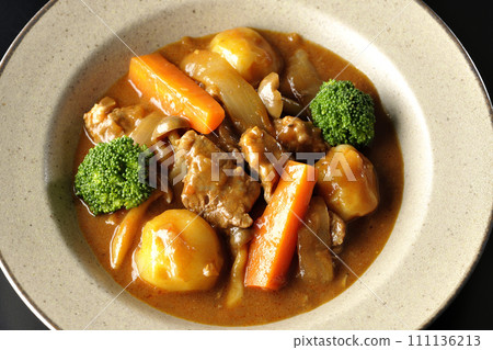 An overhead shot of beef stew with many ingredients such as broccoli, carrots, and shimeji mushrooms against a black background An overhead shot of beef stew with many ingredients such as broccoli, carrots, and shimeji mushrooms against a black background 111136213