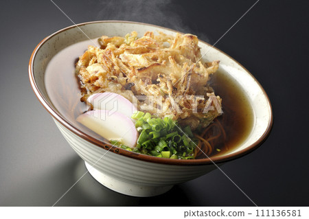 黑色背景下拍攝的熱 kakiage 蕎麥麵或天婦羅蕎麥麵，上面放著 kamaboko 和蔥 111136581