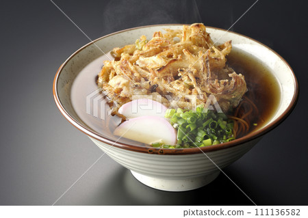 黑色背景下拍攝的熱 kakiage 蕎麥麵或天婦羅蕎麥麵，上面放著 kamaboko 和蔥 111136582