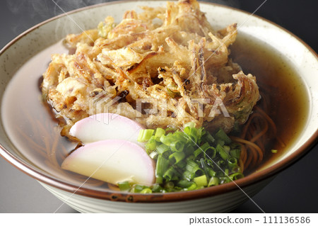 黑色背景下拍攝的熱 kakiage 蕎麥麵或天婦羅蕎麥麵,上面放著 kamaboko 和蔥 黑色背景下拍攝的熱 kakiage 蕎麥麵或天婦羅蕎麥麵,上面放著 kamaboko 和蔥 111136586