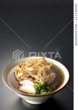 Hot kakiage soba or tempura soba topped with kamaboko and green onions photographed against a black background Hot kakiage soba or tempura soba topped with kamaboko and green onions photographed against a black background 111136595