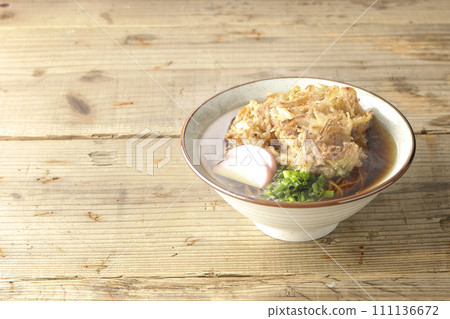 Hot kakiage soba or tempura soba topped with fish cake and green onions 111136672