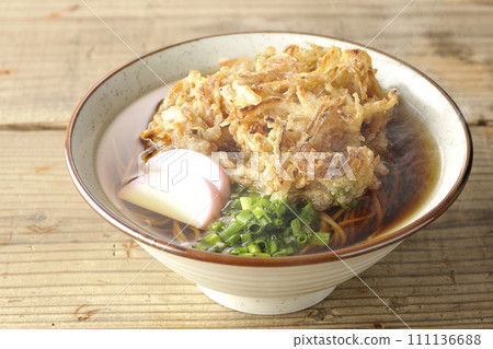 Hot kakiage soba or tempura soba topped with fish cake and green onions 111136688